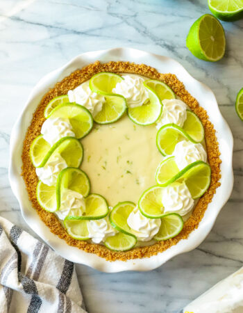 whole key lime pie in a white pie plate with striped towel