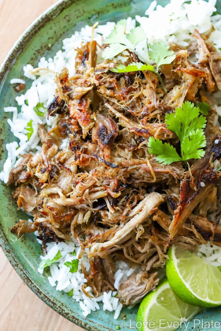 green plate of pulled pork with rice and lime slices