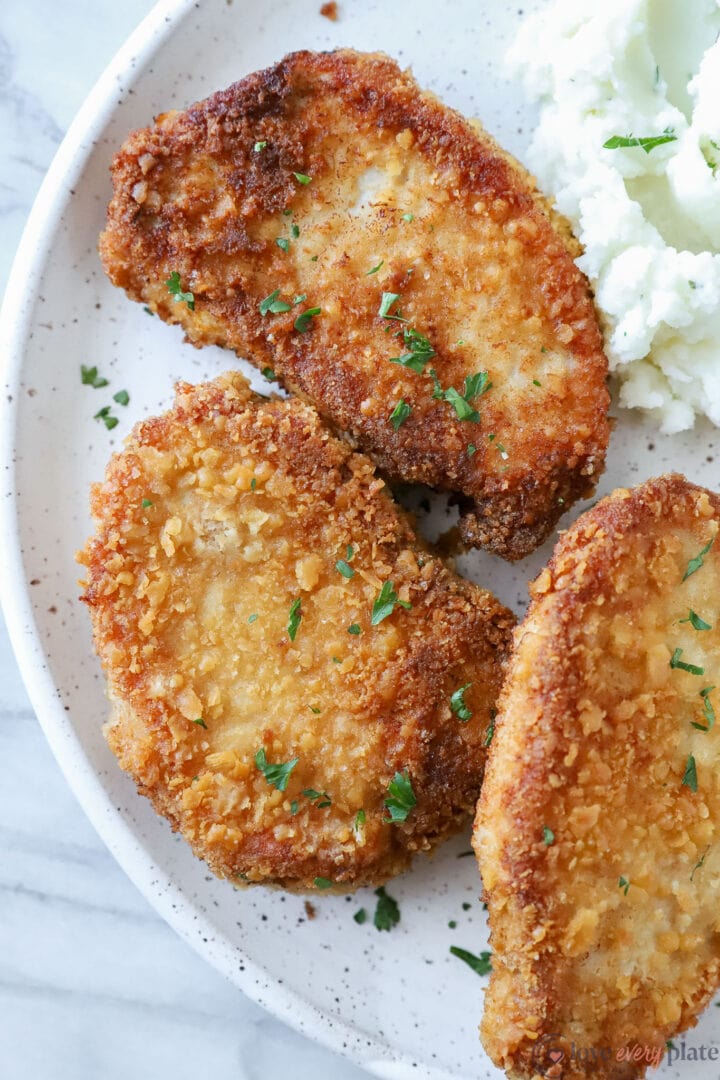 three pork chops on a white plate