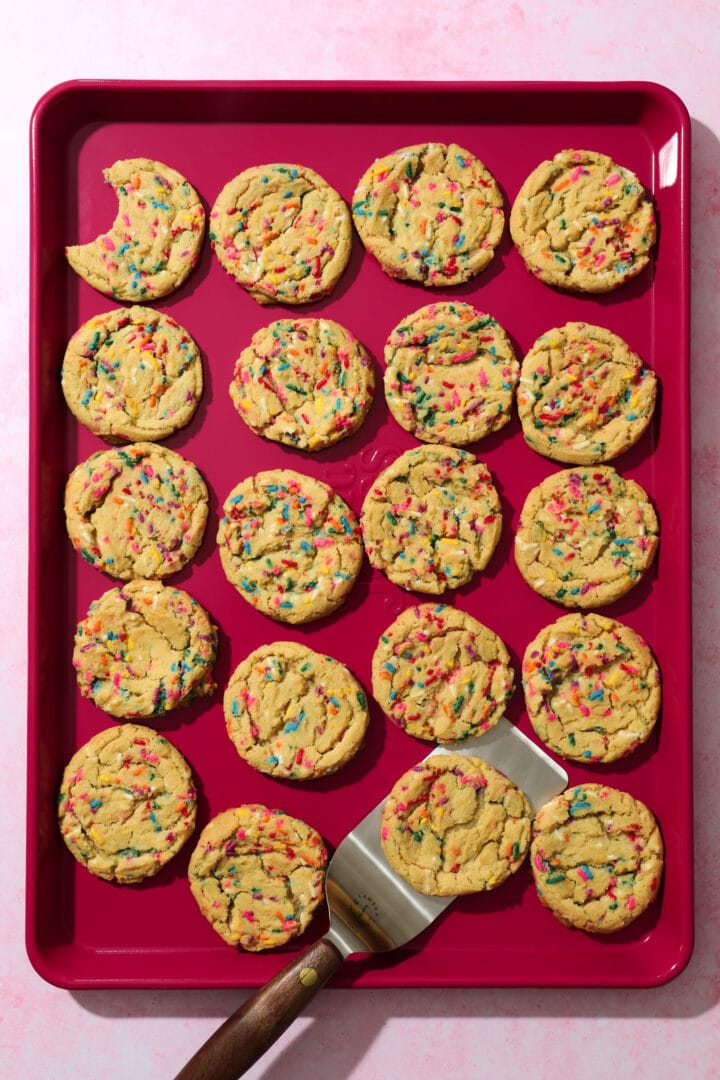 dark pink sheet pan of sprinkle cookies.