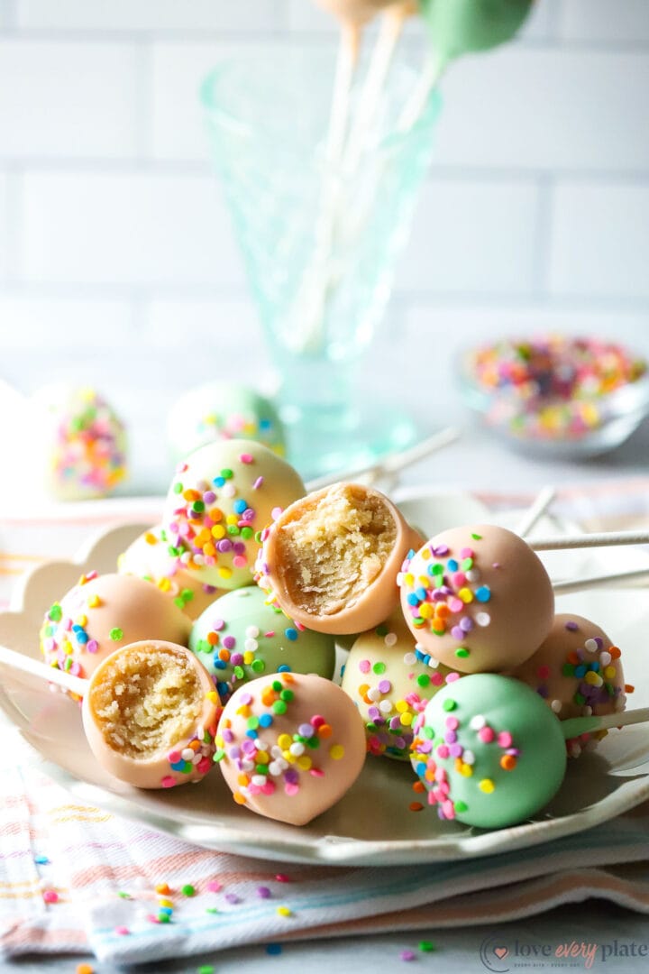 large pile of cake pops with sprinkles on a white plate