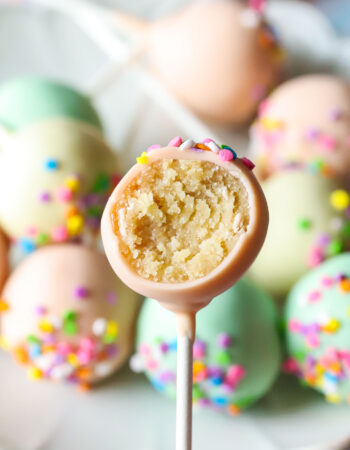 bitten vanilla cake pop with a plate of cake pops in the background