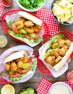 top view of three shrimp sandwiches with pickles, lettuce and tomato