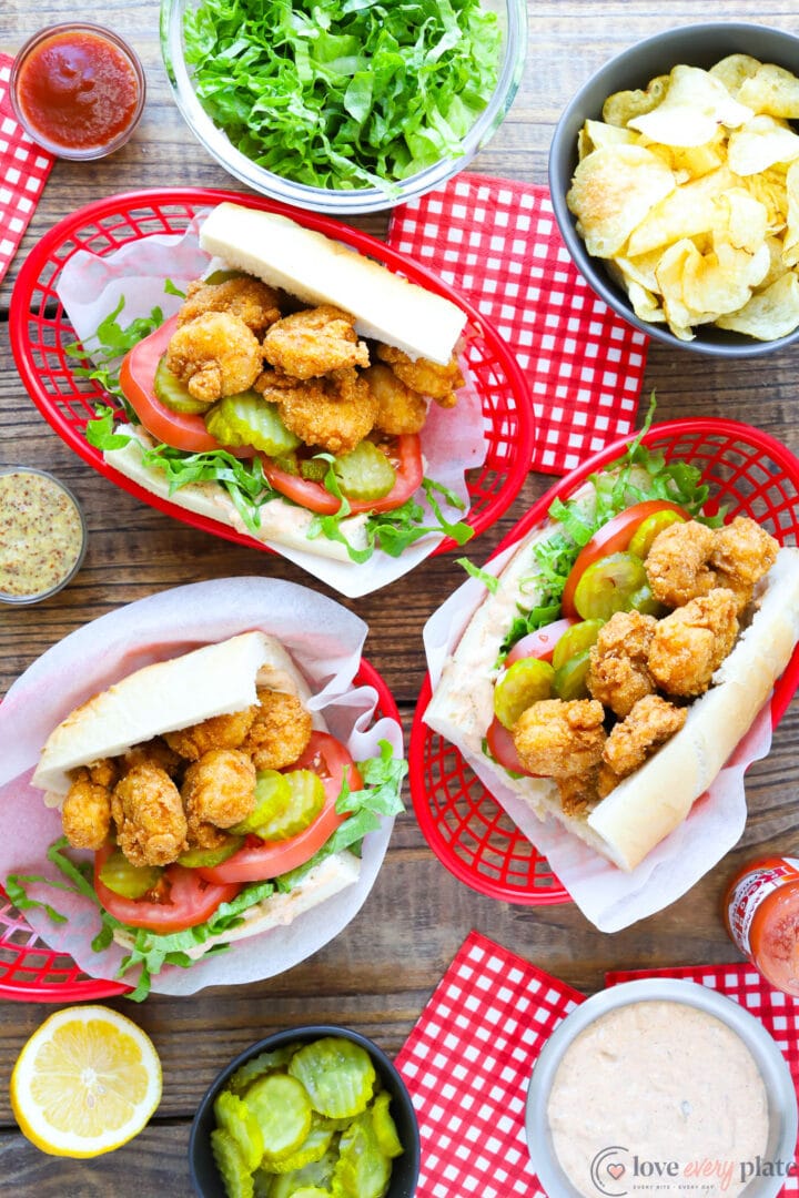 top view of three shrimp sandwiches with pickles, lettuce and tomato