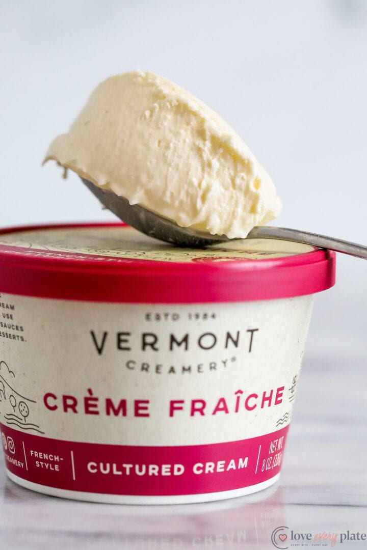 jar of creme fraiche with a spoonful of cream on top of the lid