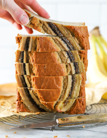 stack of banana bread slices with a hand taking one from the top