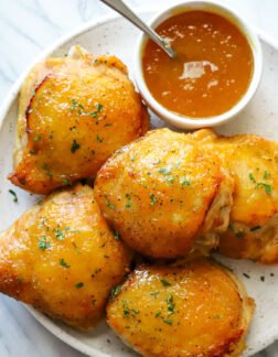 plate of peach glazed chicken thighs and small bowl of peach glaze