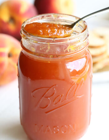 jar of peach preserves with peaches in the background