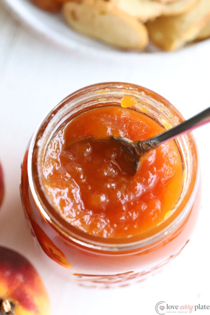 jar of peach preserves with a spoon