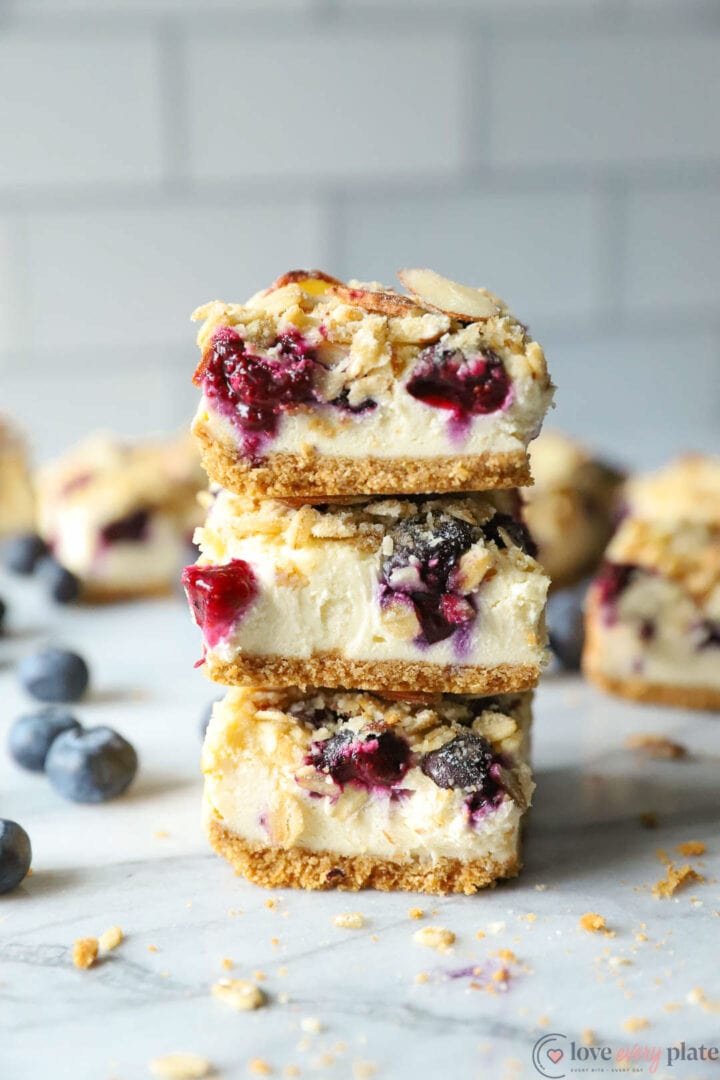 stack of three cheesecake bars with blueberries and almond crunch