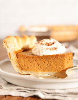 slice of pumpkin pie with a dollop of whipped cream on top