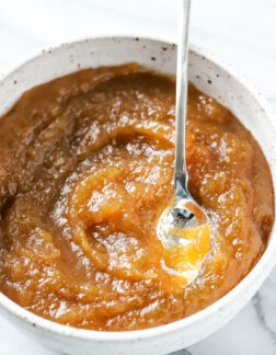 white bowl of apple butter with a silver spoon, top view