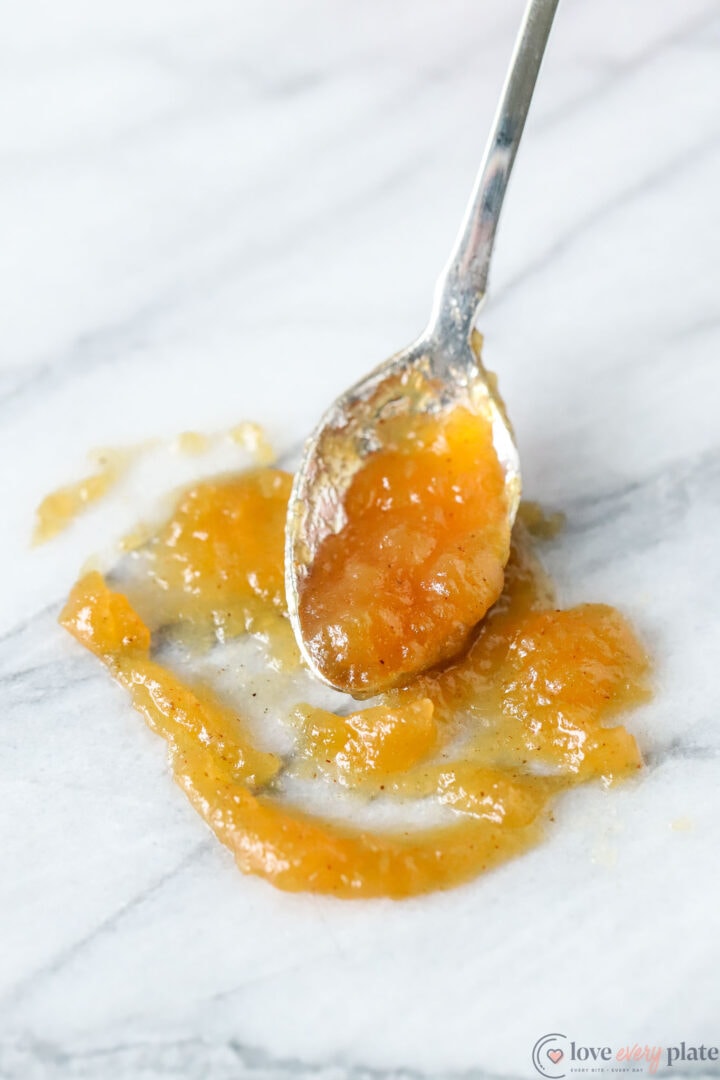 spoonful of apple butter that has spilled onto a white marble board