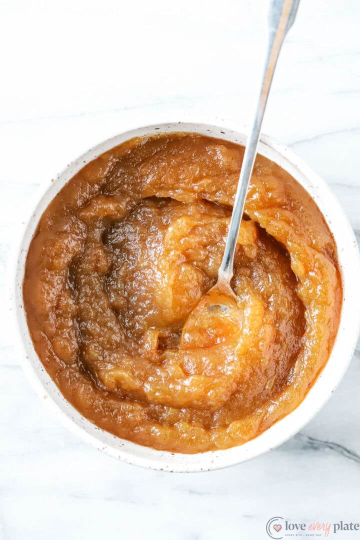 white bowl of apple butter with a silver spoon, top view