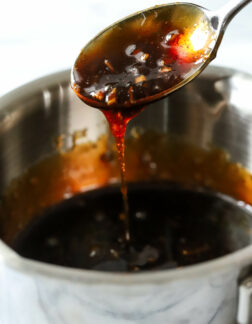 small steel pot of soy glaze with a spoon dipped into the glaze