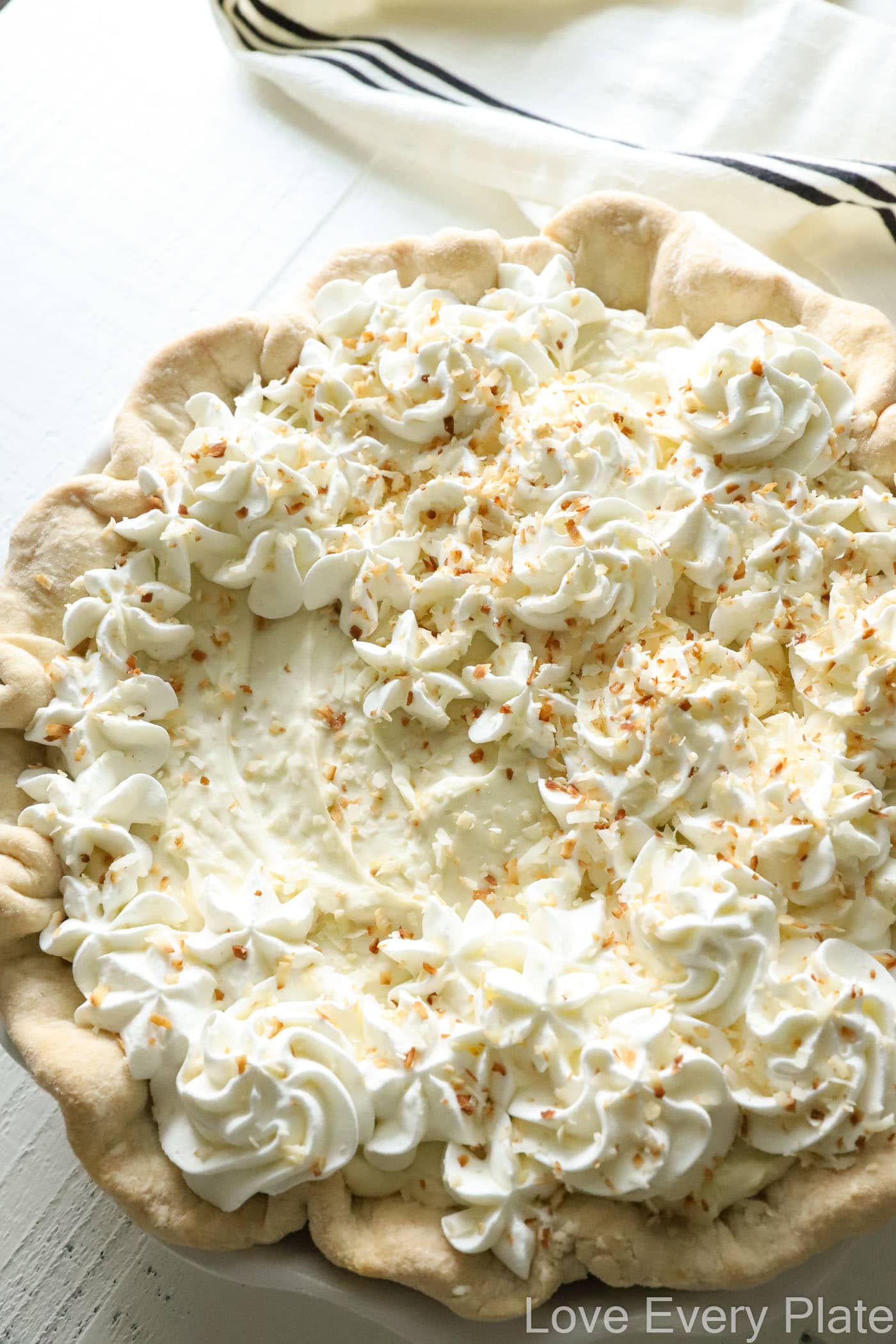 whole coconut cream pie with a small amount of whipped cream on top