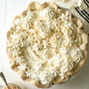whole coconut cream pie with a small amount of whipped cream on top