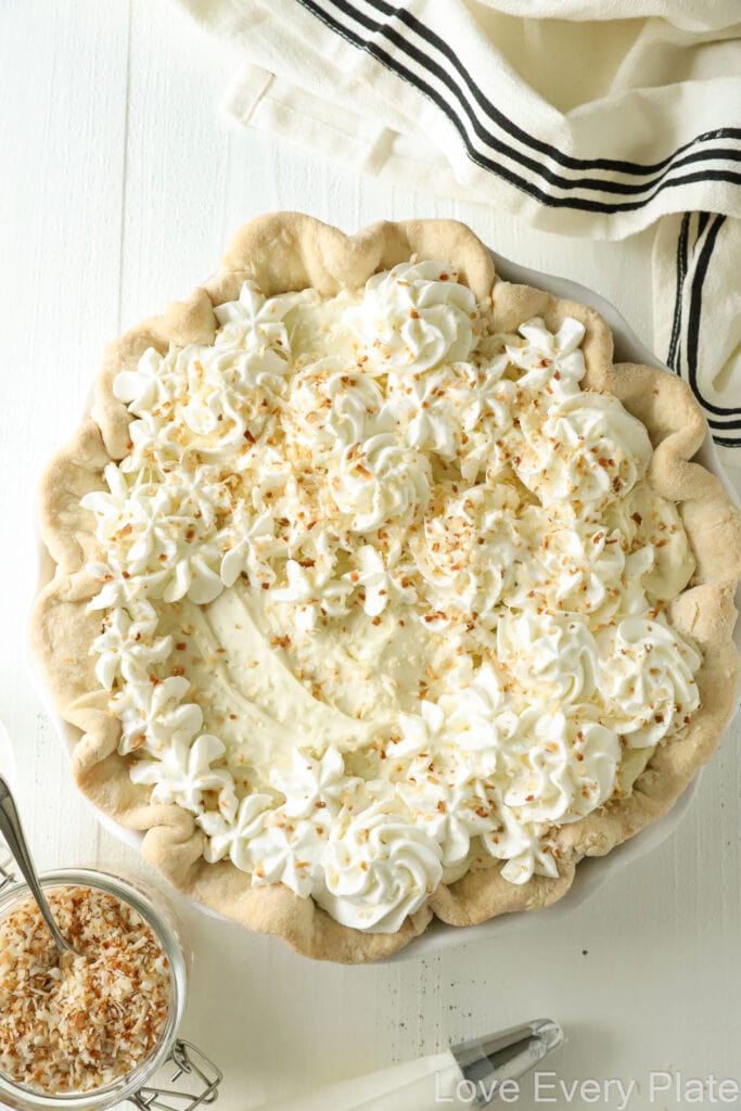 whole coconut cream pie with a small amount of whipped cream on top