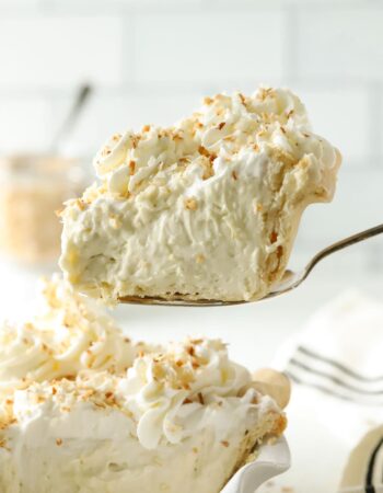 slice of coconut cream pie being lifted from a white pie plate