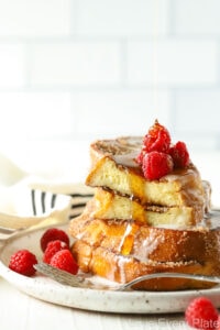 slices of french toast on a white plate with raspberries