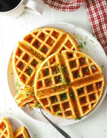 two waffles on a white plate with a cup of coffee