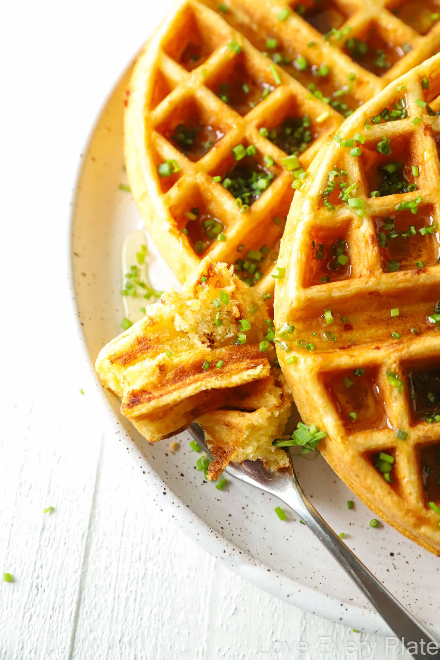 a bite of waffle next to a whole waffle on a white plate