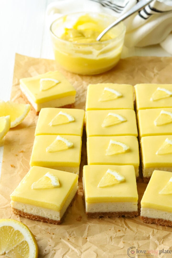 lemon cheesecake squares with a bowl of lemon curd and lemon slices