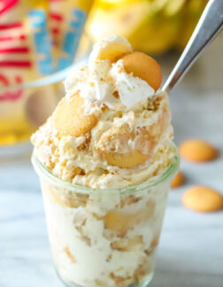 cup of banana pudding with whipped cream and vanilla cookies and spoon