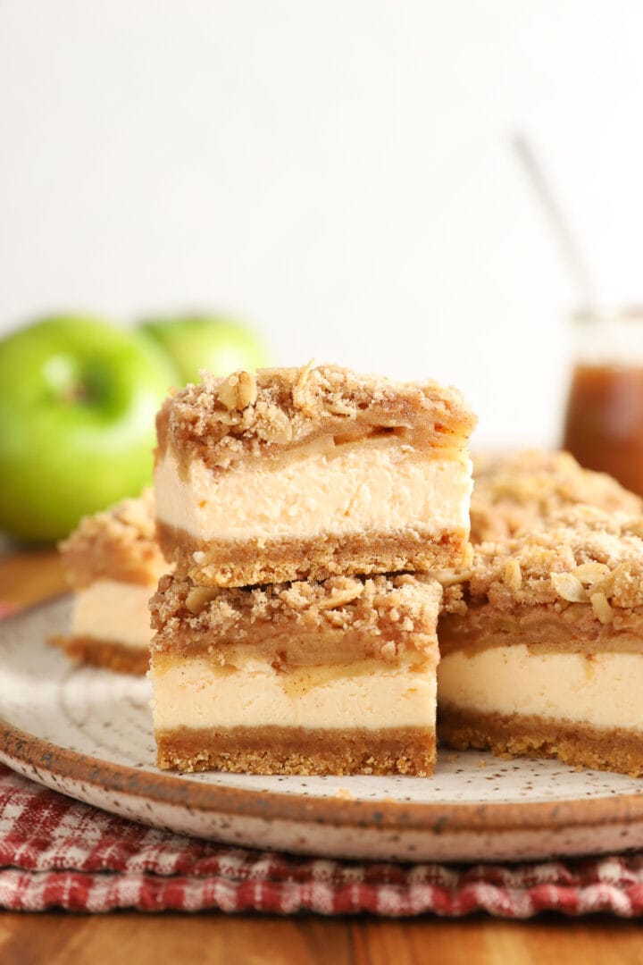 small stack of caramel apple cheesecake bars being drizzled with caramel sauce