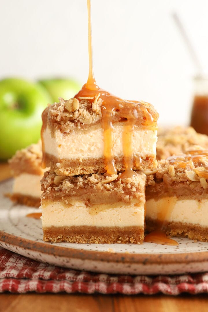 small stack of caramel apple cheesecake bars being drizzled with caramel sauce