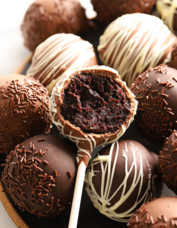 pile of chocolate cake pops with white chocolate drizzle and sprinkles