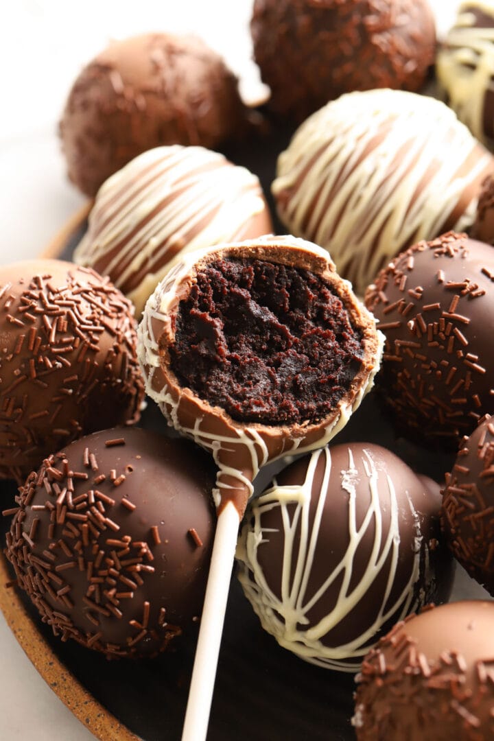 pile of chocolate cake pops with white chocolate drizzle and sprinkles