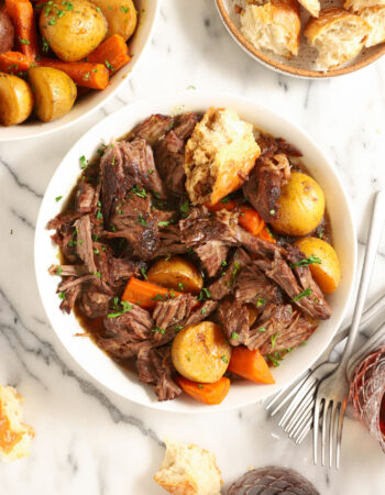 white bowl of beef roast with potatoes and carrots