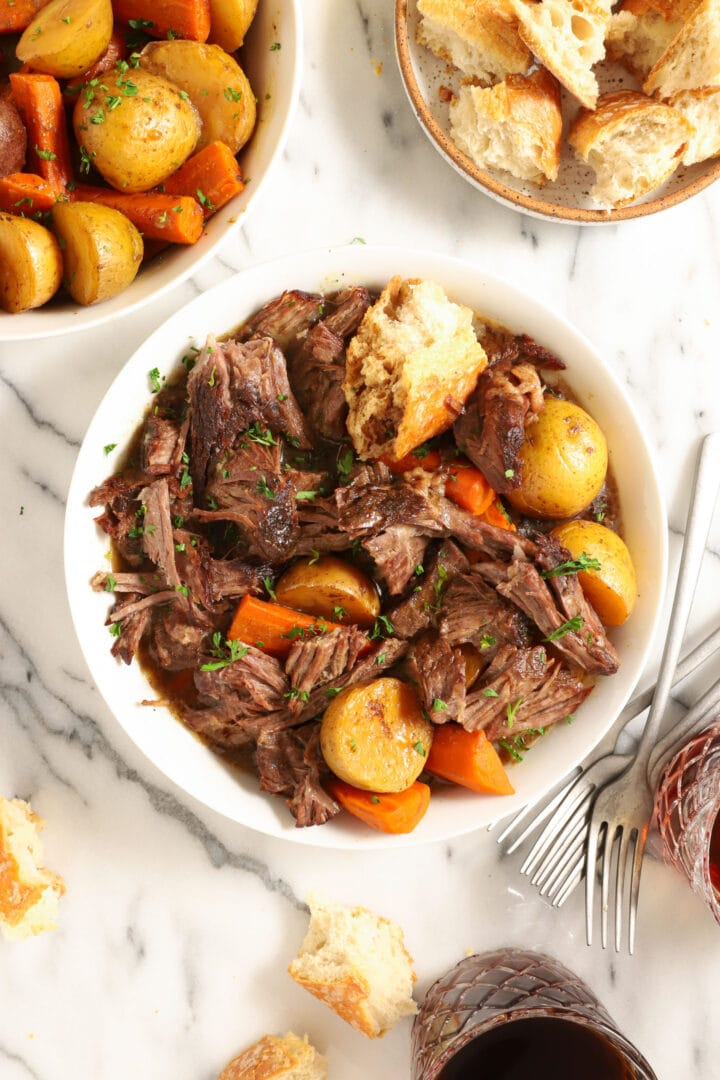 white bowl of beef roast with potatoes and carrots