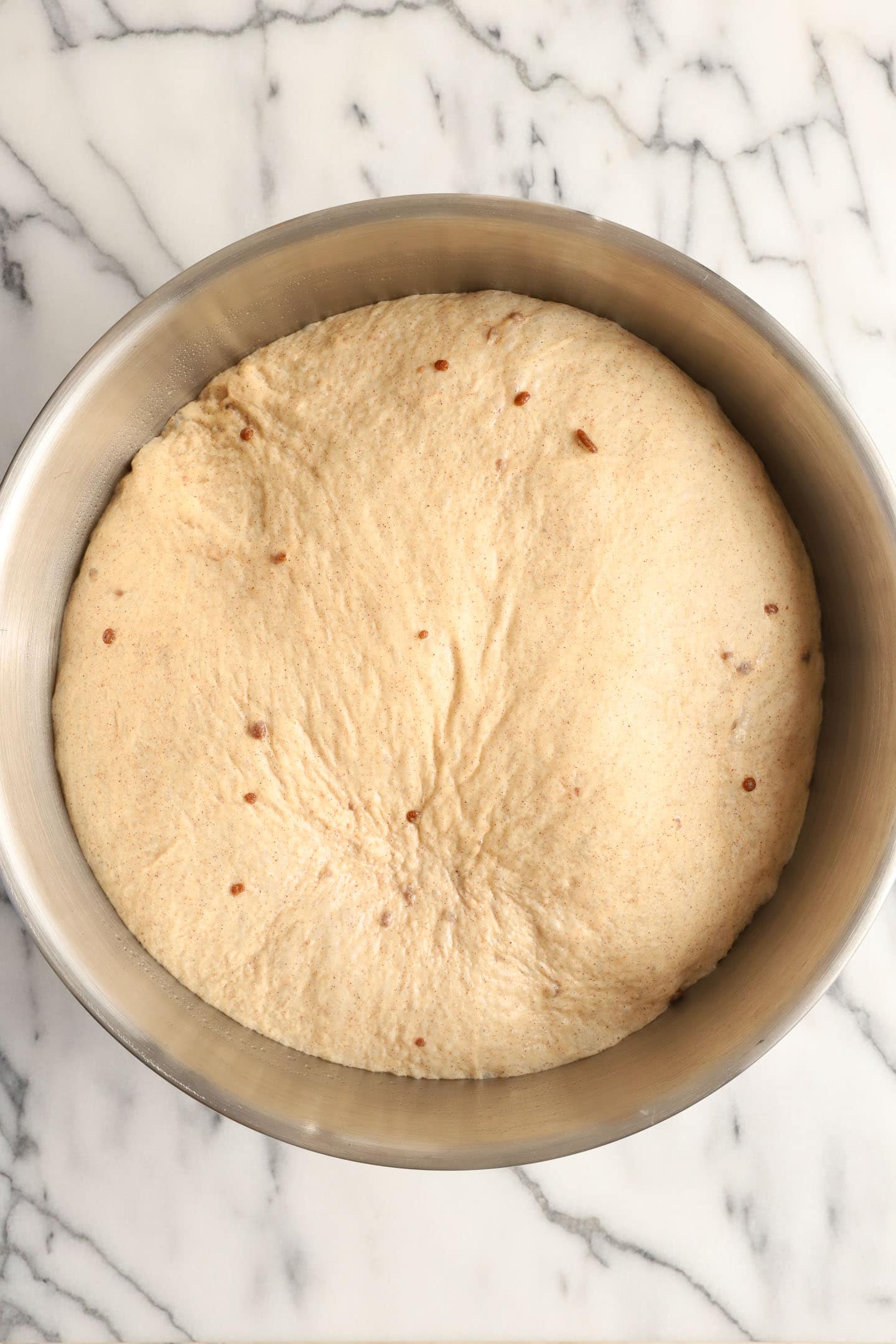 a large metal mixing bowl of cinnamon dough