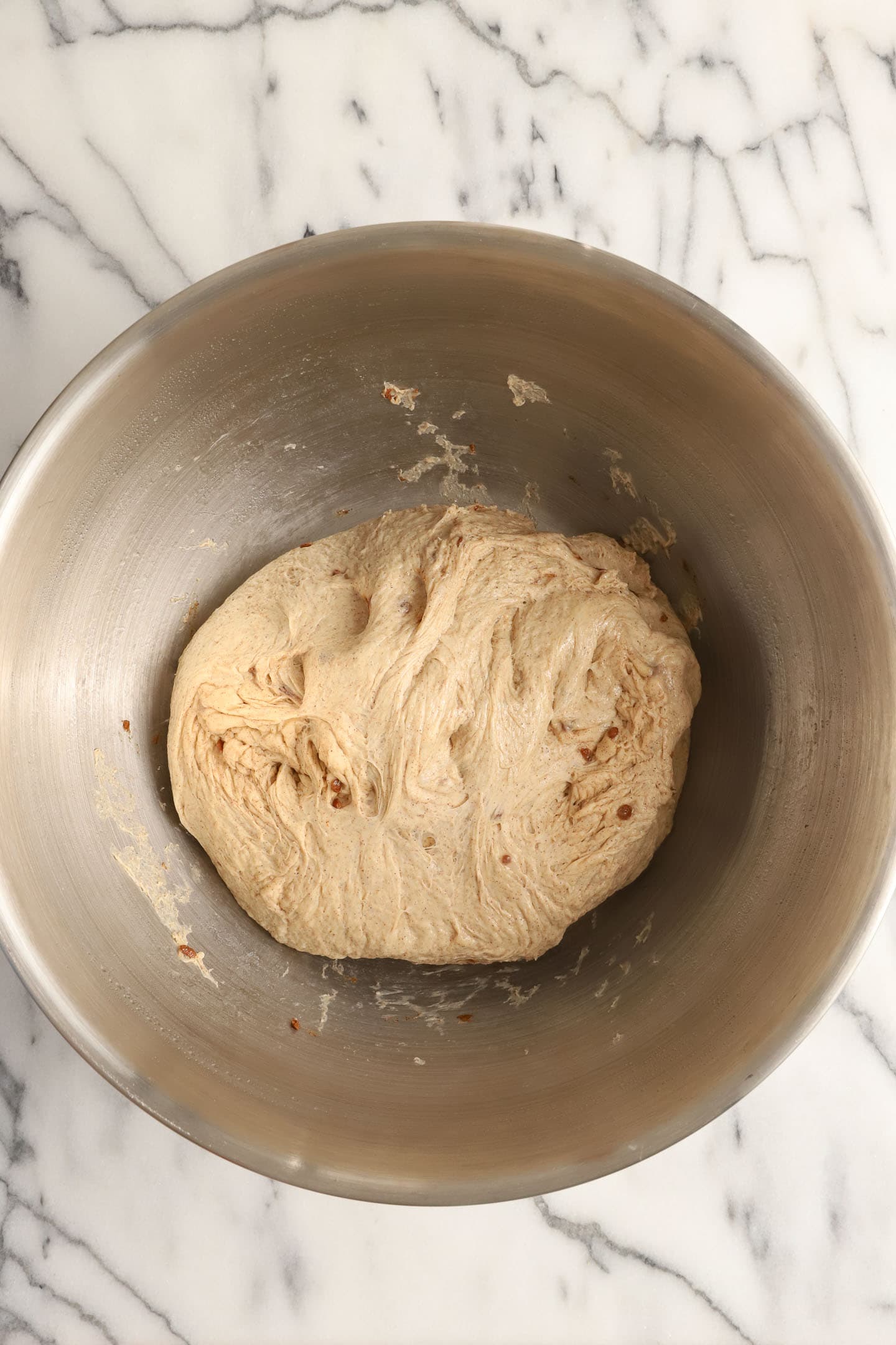 a large metal mixing bowl of cinnamon dough
