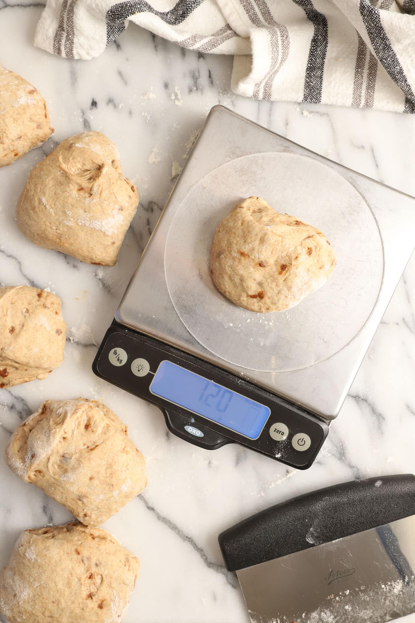 a digital scale being used to weigh each ball of cinnamon bagel dough