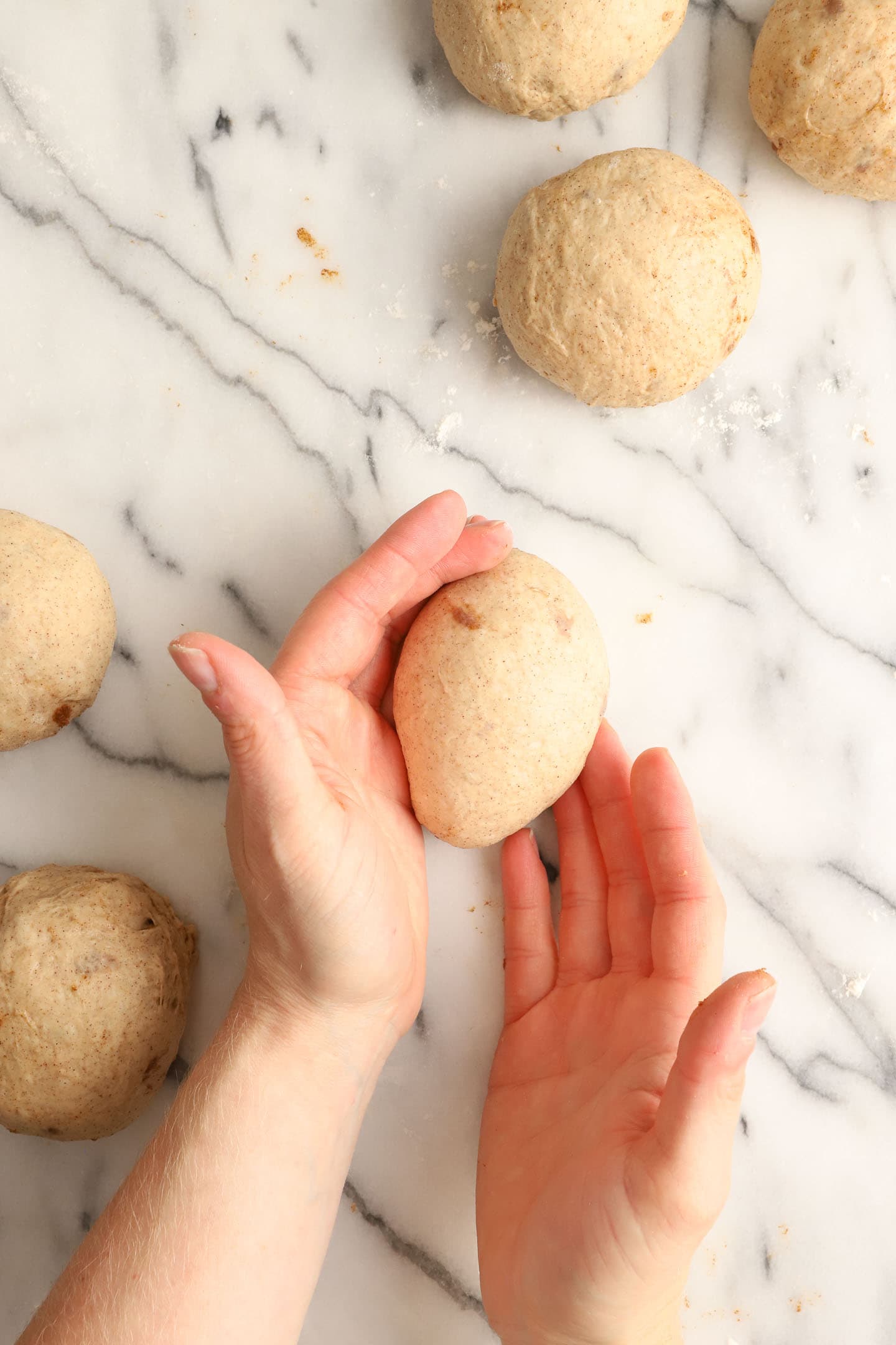 two hands demonstrating how to form a dough ball shape