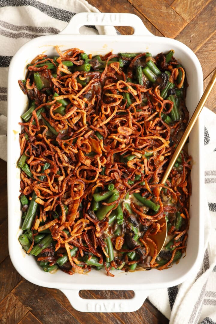 a white rectangular baking dish with green bean casserole, topped with french fried onions