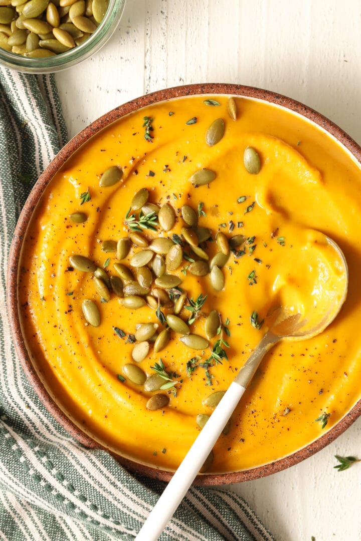 bowl of butternut squash soup garnished with pepitas and fresh thyme