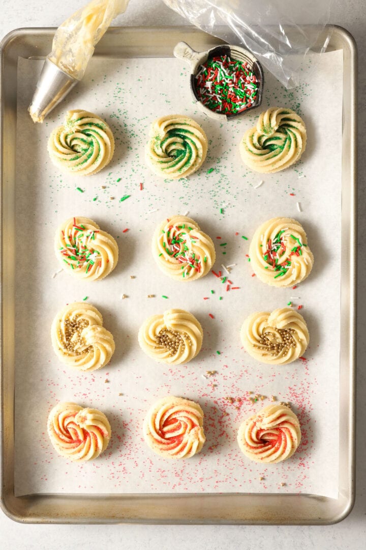 baking sheet of raw christmas cookies that have been decorated and are ready to bake