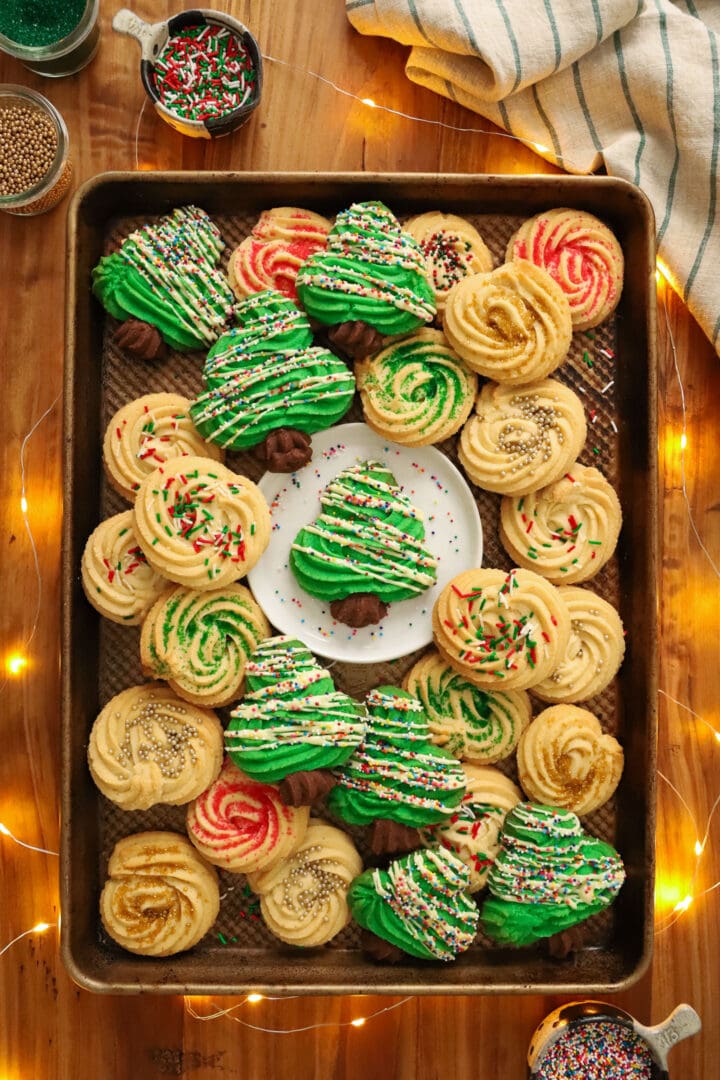 top shot of a christmas tree shaped cookie, surrounded by additional christmas cookies on a large baking tray