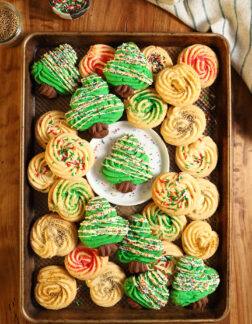 top shot of a christmas tree shaped cookie, surrounded by additional christmas cookies on a large baking tray