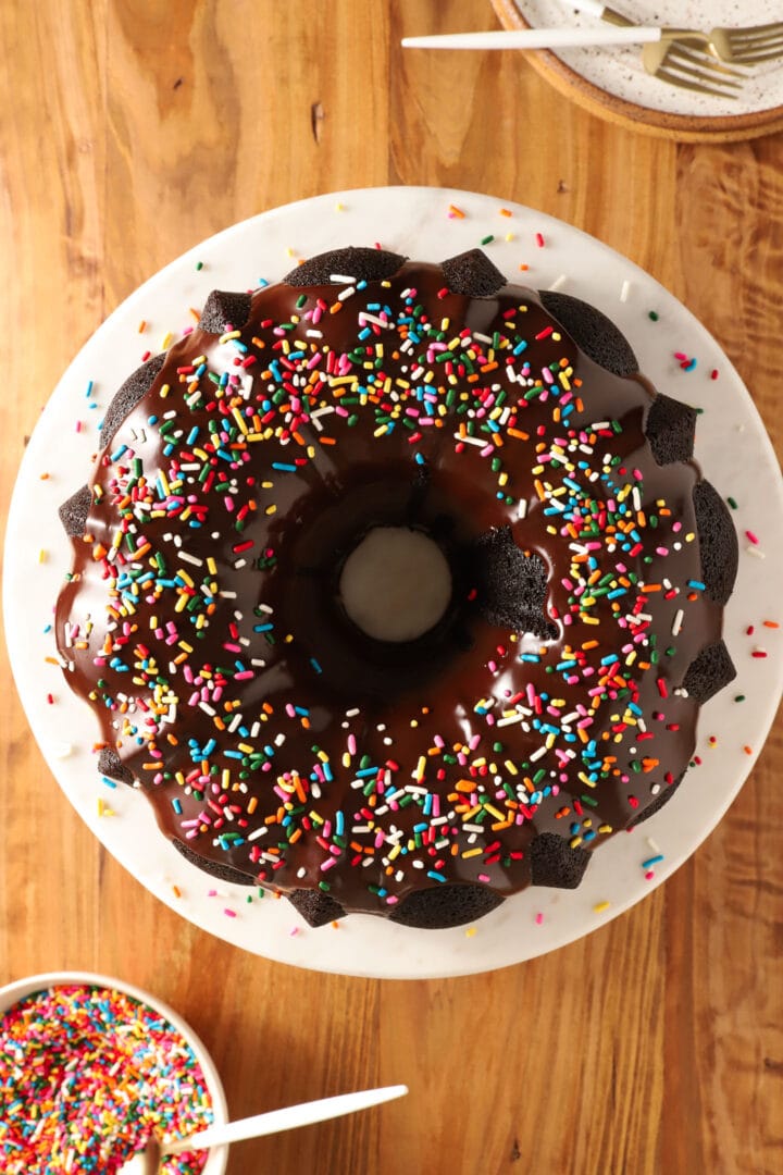 whole chocolate bundt cake on a white marble and wooden platter