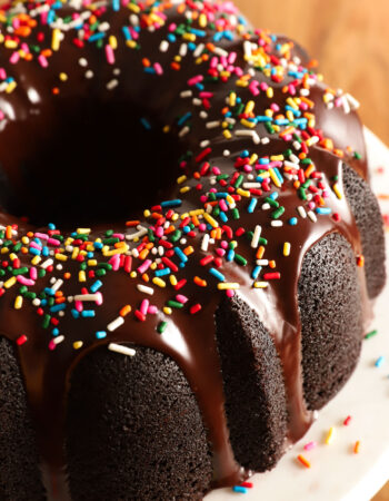 whole chocolate bundt cake on a white marble and wooden platter