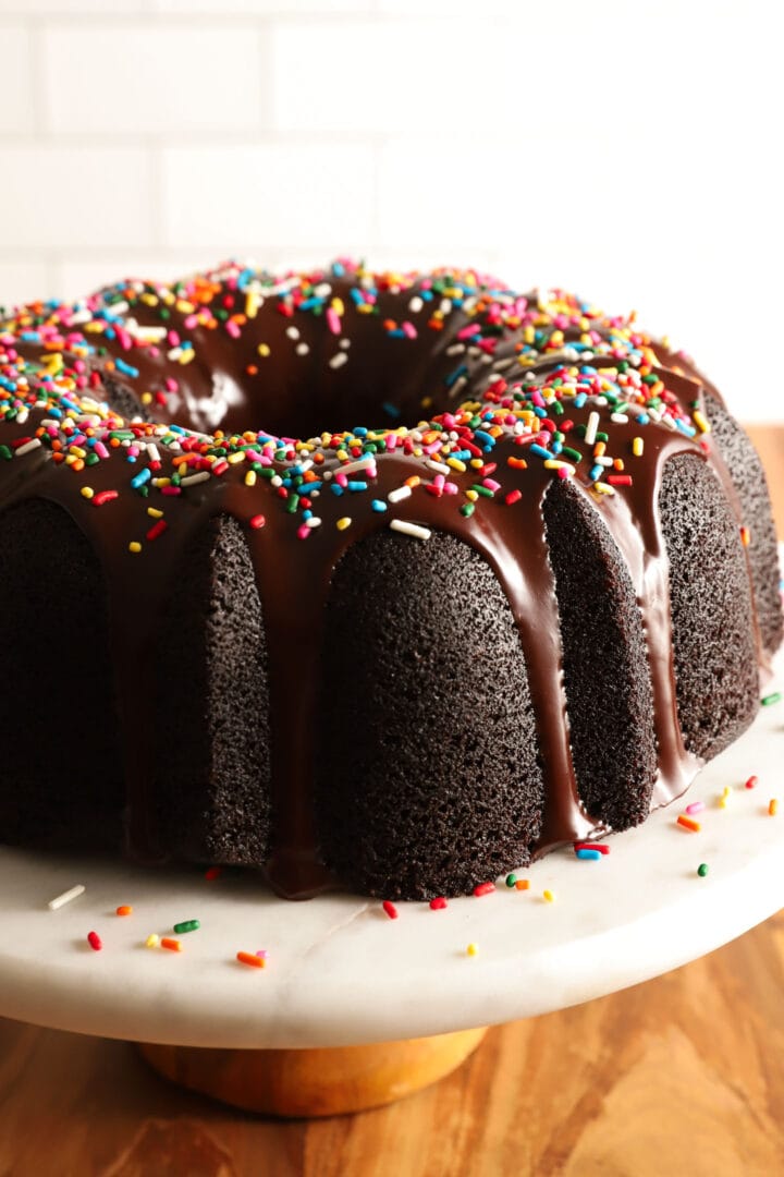 whole chocolate bundt cake on a white marble and wooden platter