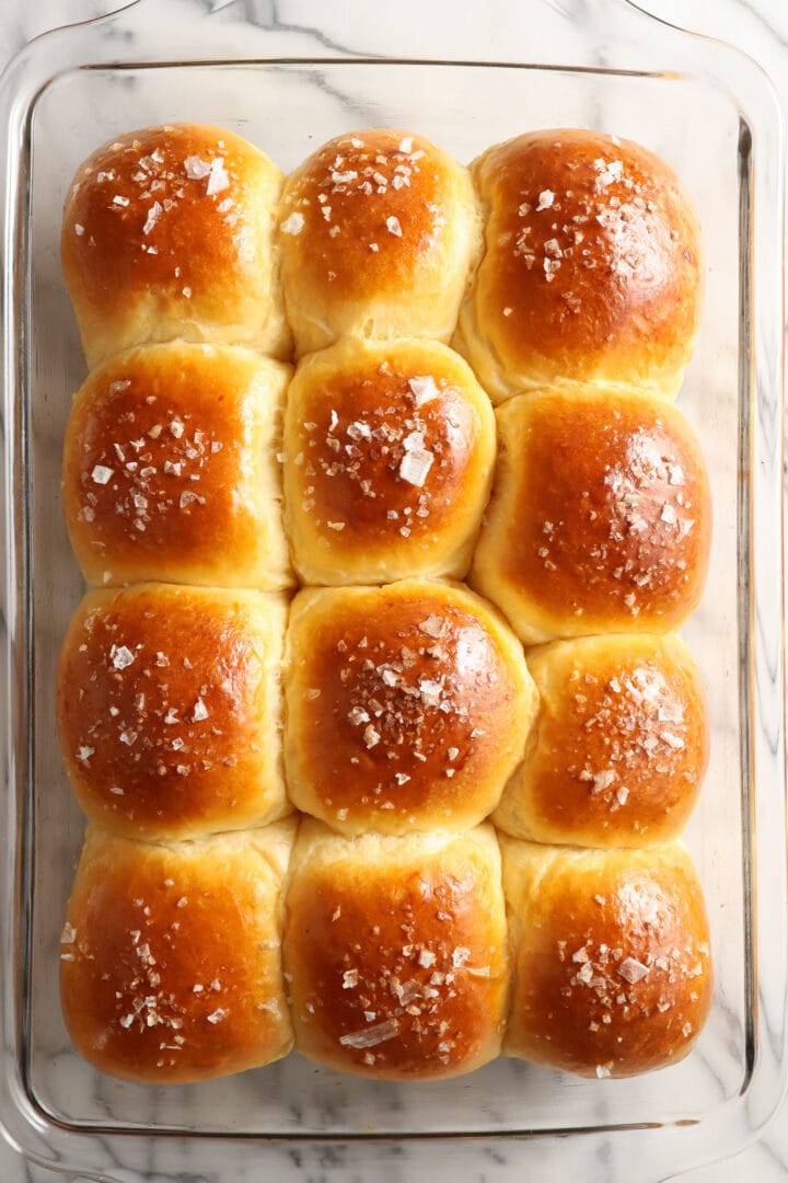 tray of dinner rolls with salt on top.