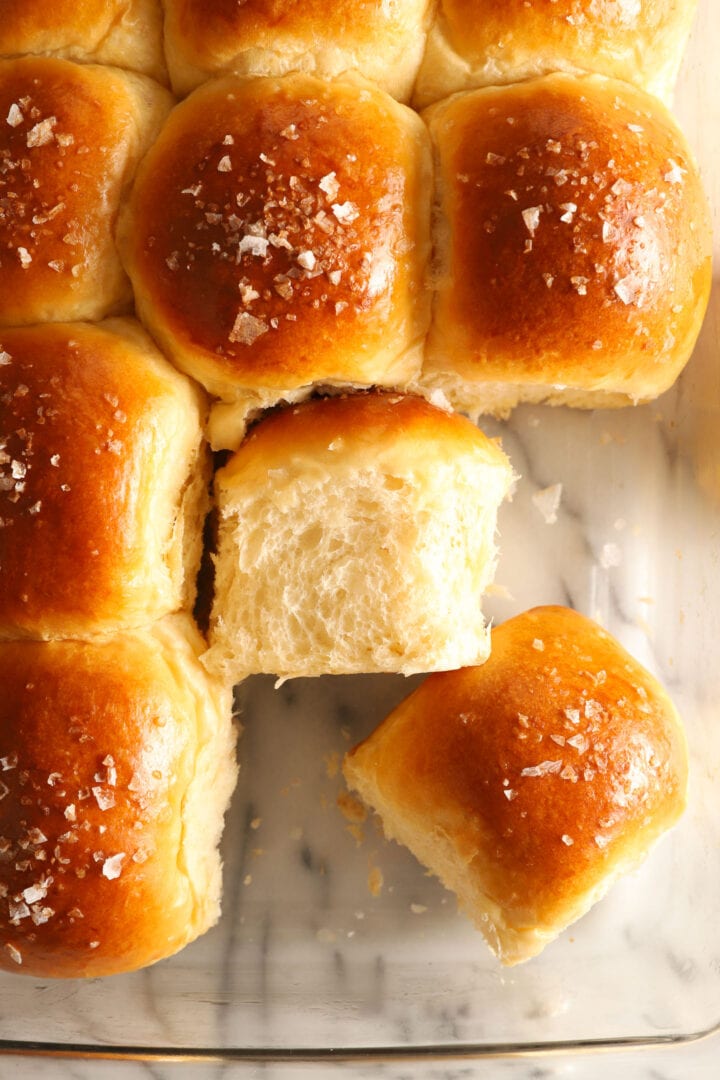 tray of dinner rolls with salt on top. Two rolls are facing different directions.