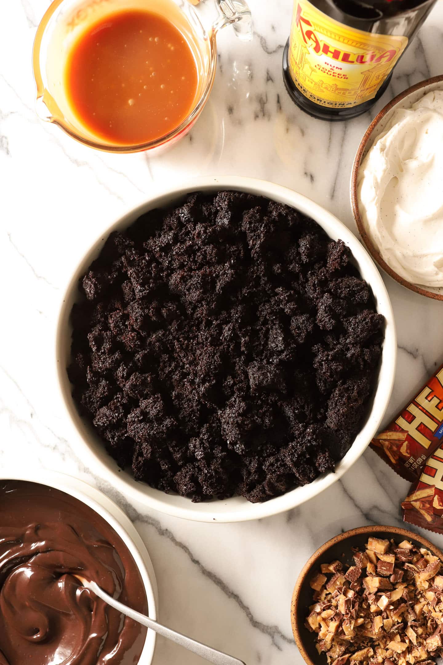 top view of dirt cake trifle ingredients in assorted white bowls