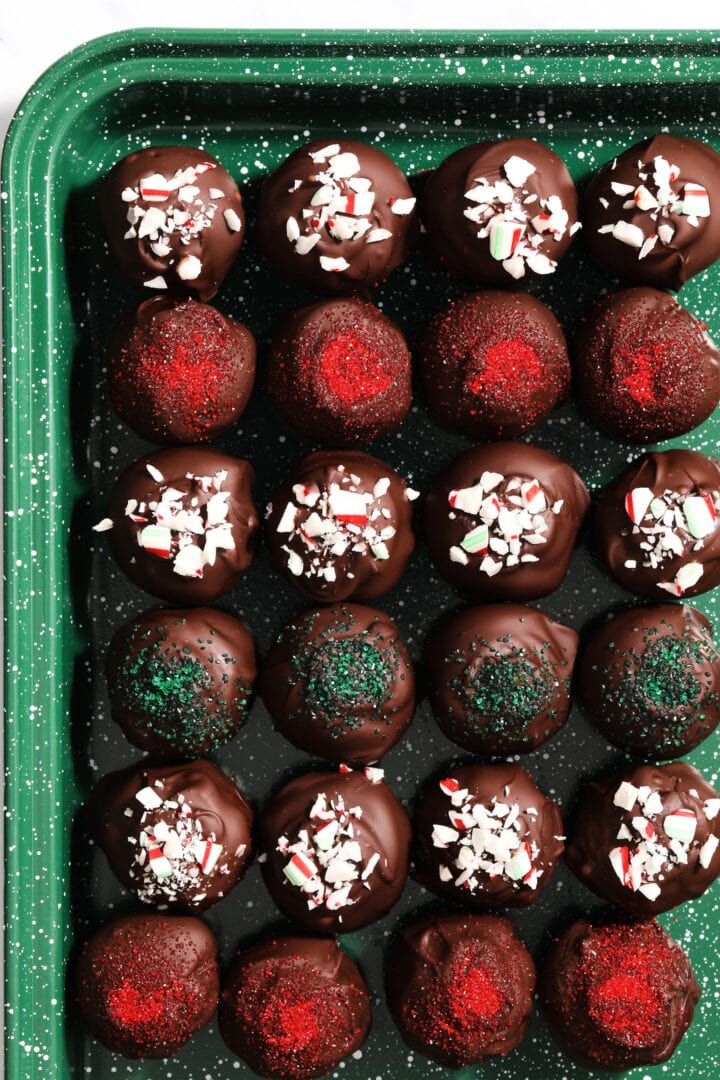 green speckled tray of oreo truffles that have been decorated with crushed candy canes.